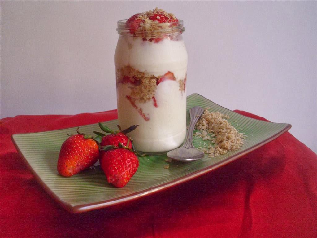 A layered Greek yogurt parfait with berries and granola in a glass jar