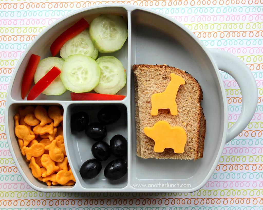 A colorful bento box filled with hummus, vegetables and crackers